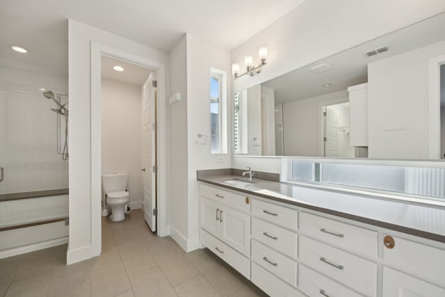 bathroom featuring vanity, tile patterned floors, toilet, and a tile shower