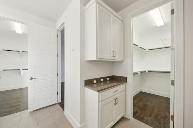 bar with white cabinetry and light tile patterned floors