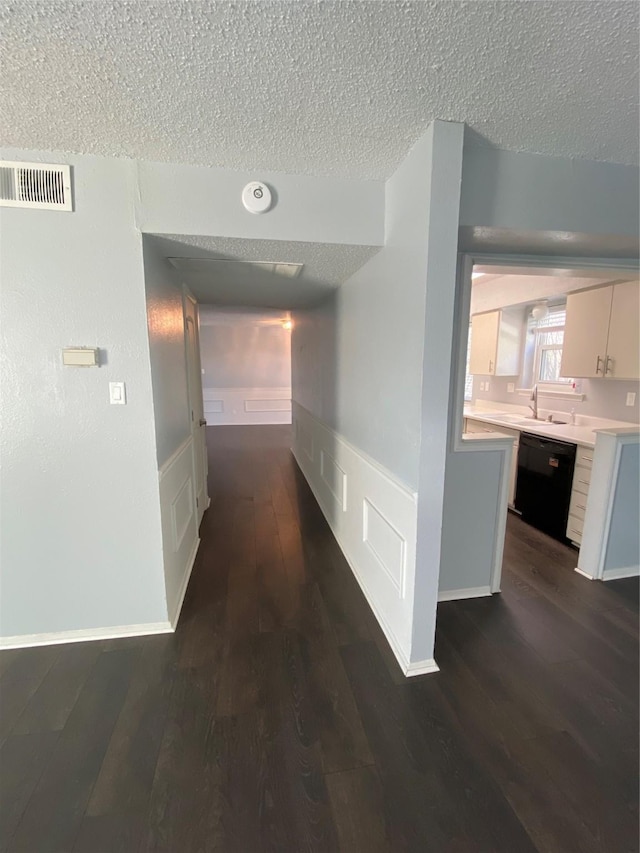 corridor with dark hardwood / wood-style floors and a textured ceiling