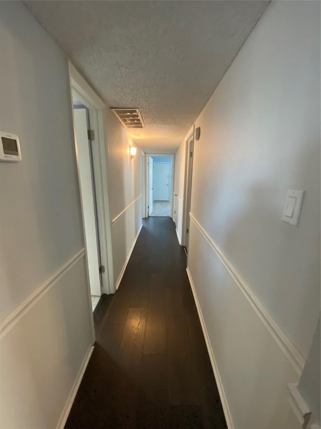 hallway featuring dark hardwood / wood-style floors and a textured ceiling