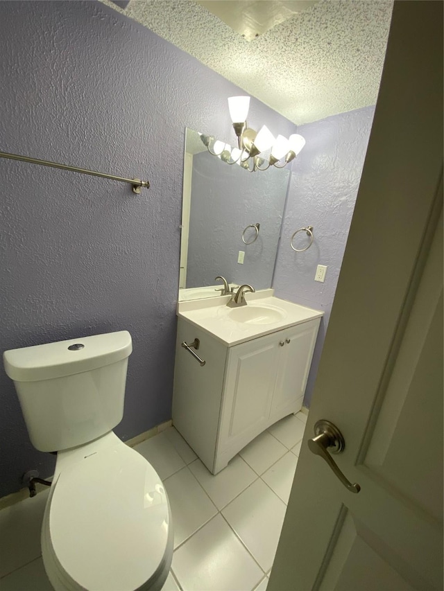 bathroom with an inviting chandelier, vanity, toilet, tile patterned floors, and a textured ceiling