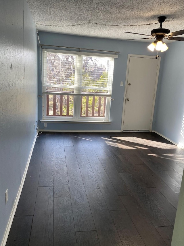 unfurnished room featuring ceiling fan, dark hardwood / wood-style floors, and a textured ceiling