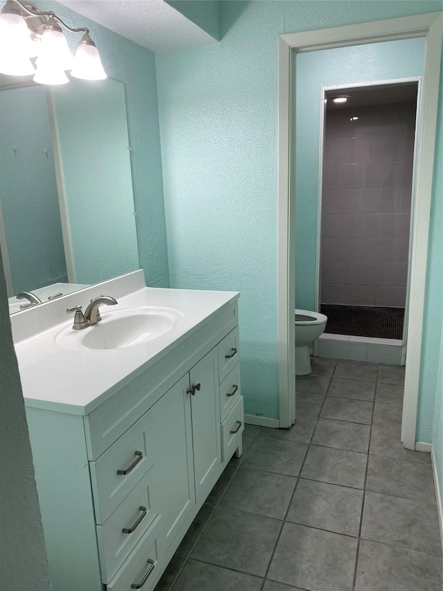 bathroom featuring tile patterned flooring, vanity, toilet, and tiled shower