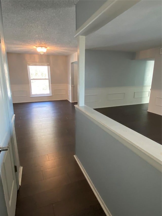 hallway with dark wood-type flooring and a textured ceiling