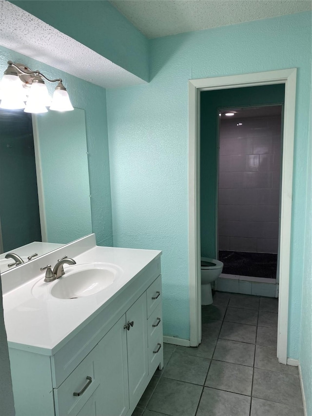 bathroom featuring a tile shower, tile patterned flooring, vanity, toilet, and a textured ceiling