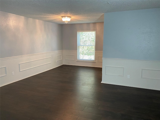 empty room with dark hardwood / wood-style floors and a textured ceiling