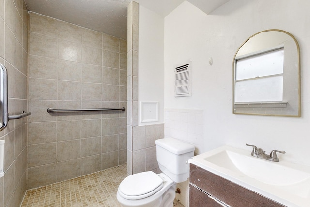 bathroom with vanity, tiled shower, and toilet