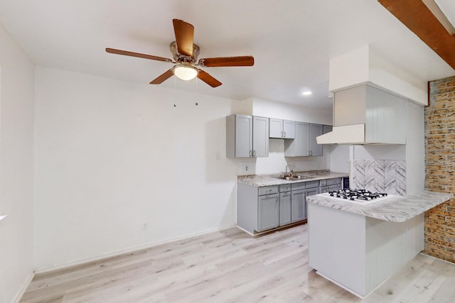 kitchen featuring sink, gray cabinetry, white gas stovetop, kitchen peninsula, and light hardwood / wood-style floors