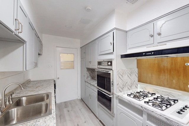 kitchen featuring sink, light hardwood / wood-style flooring, gray cabinets, white gas stovetop, and stainless steel double oven