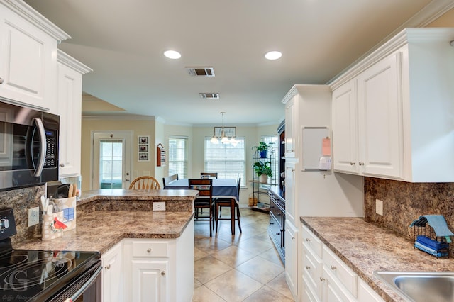 kitchen with black range with electric stovetop, kitchen peninsula, hanging light fixtures, and white cabinets