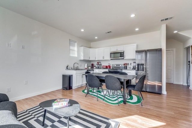 interior space with white cabinetry, stainless steel appliances, a kitchen breakfast bar, a kitchen island, and light wood-type flooring