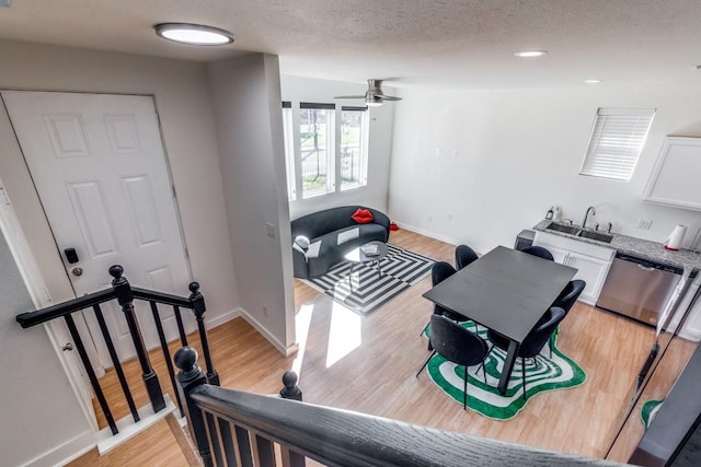 interior space featuring sink, ceiling fan, a textured ceiling, and light wood-type flooring