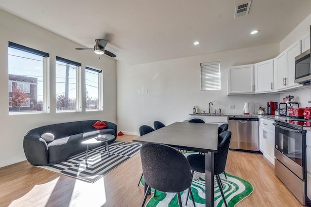 kitchen featuring white cabinetry, appliances with stainless steel finishes, ceiling fan, light stone countertops, and light hardwood / wood-style floors