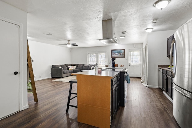 kitchen featuring stainless steel refrigerator, a breakfast bar area, dark hardwood / wood-style flooring, island exhaust hood, and a center island