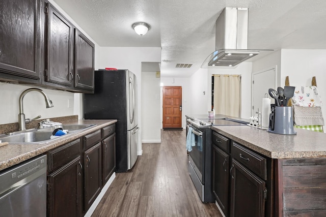 kitchen with sink, appliances with stainless steel finishes, dark brown cabinets, island range hood, and dark hardwood / wood-style flooring