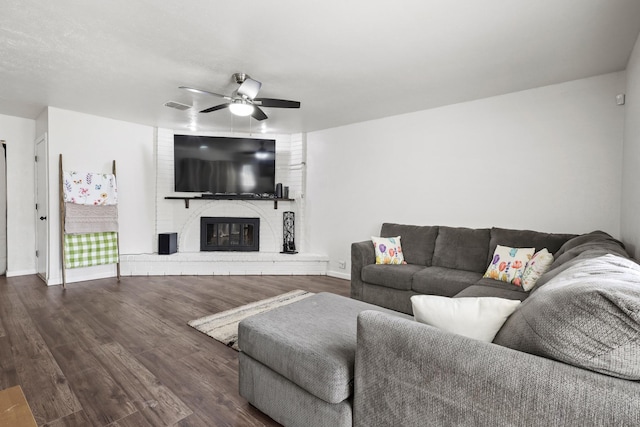 living room featuring ceiling fan, a fireplace, and dark hardwood / wood-style floors