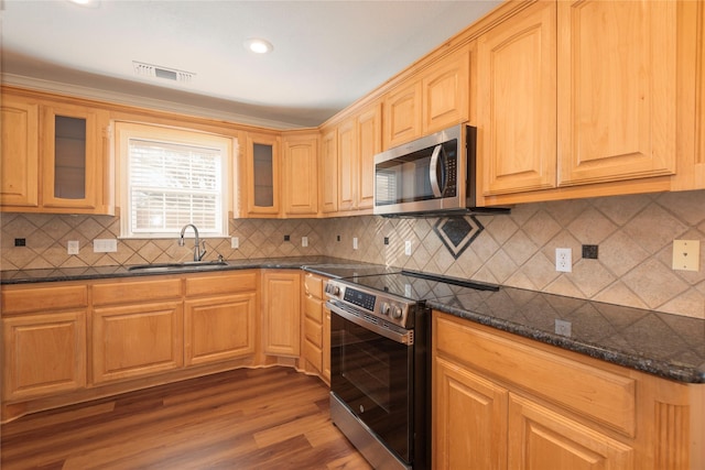 kitchen featuring sink, appliances with stainless steel finishes, dark stone countertops, backsplash, and wood-type flooring