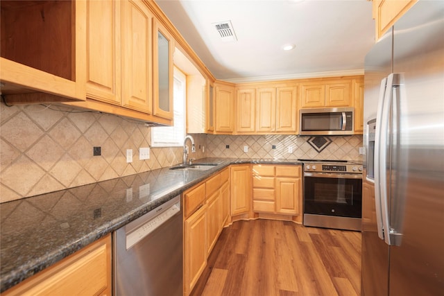 kitchen with sink, dark wood-type flooring, appliances with stainless steel finishes, dark stone counters, and light brown cabinets