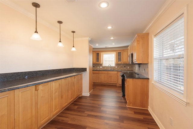 kitchen featuring decorative light fixtures, sink, dark stone countertops, ornamental molding, and stainless steel appliances