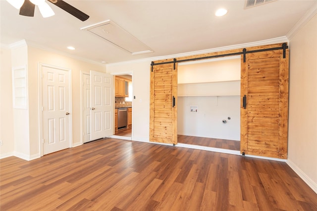 unfurnished bedroom featuring crown molding, a barn door, ceiling fan, and hardwood / wood-style flooring