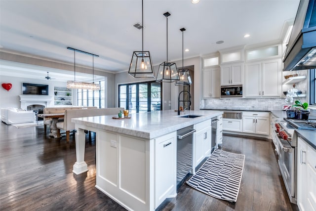 kitchen featuring white cabinetry, black microwave, sink, double oven range, and a center island with sink