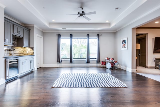 exercise room with wine cooler, a tray ceiling, dark hardwood / wood-style flooring, and sink