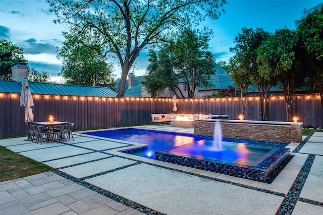 pool at dusk with a fire pit and a patio