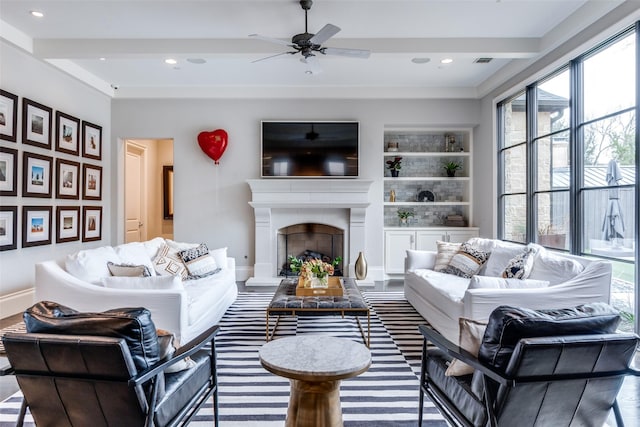 living room featuring ceiling fan, built in shelves, and beamed ceiling