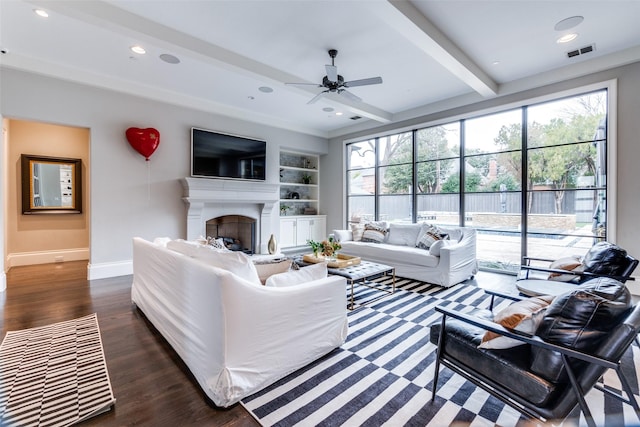 living room featuring dark wood-type flooring, ceiling fan, beam ceiling, and built in shelves