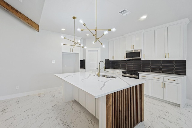 kitchen with a kitchen island with sink, sink, decorative light fixtures, and white cabinets