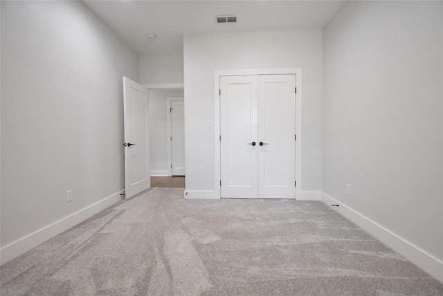 unfurnished bedroom with a closet and light carpet