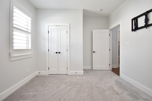 unfurnished bedroom featuring light colored carpet and a closet