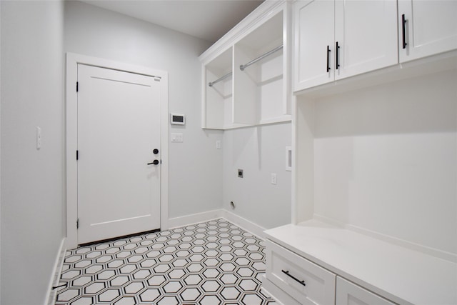 clothes washing area featuring electric dryer hookup and cabinets