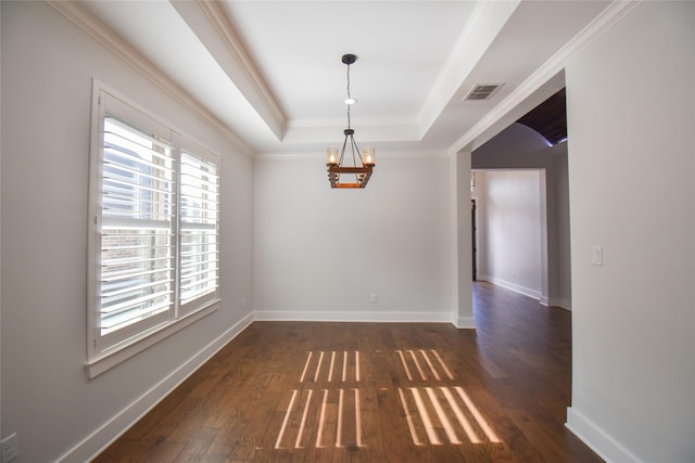 spare room with ornamental molding, dark wood-type flooring, a notable chandelier, and a tray ceiling