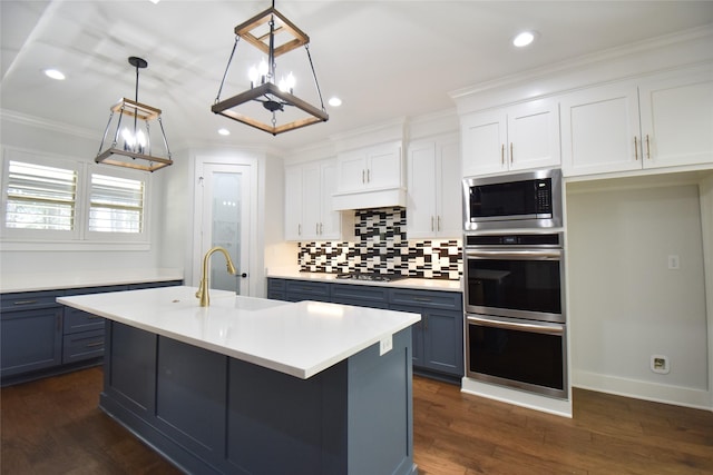 kitchen featuring appliances with stainless steel finishes, pendant lighting, white cabinetry, sink, and a kitchen island with sink