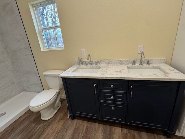 bathroom featuring vanity, tiled shower, hardwood / wood-style floors, and toilet