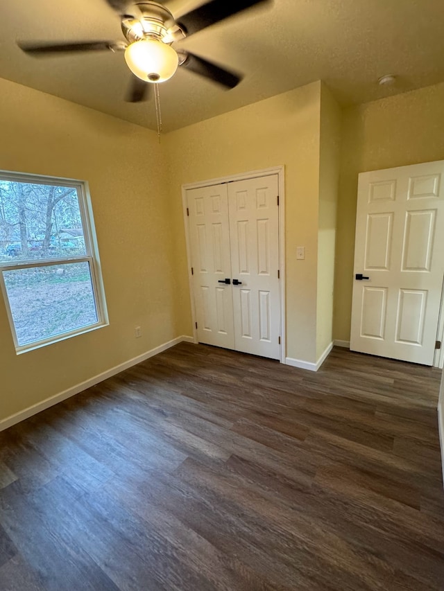 unfurnished bedroom featuring dark wood-type flooring, a closet, and ceiling fan