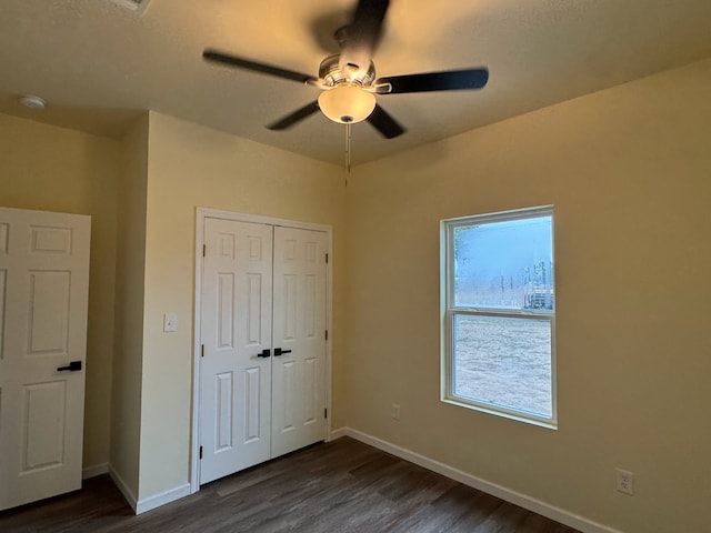 unfurnished bedroom with ceiling fan, dark hardwood / wood-style flooring, and a closet