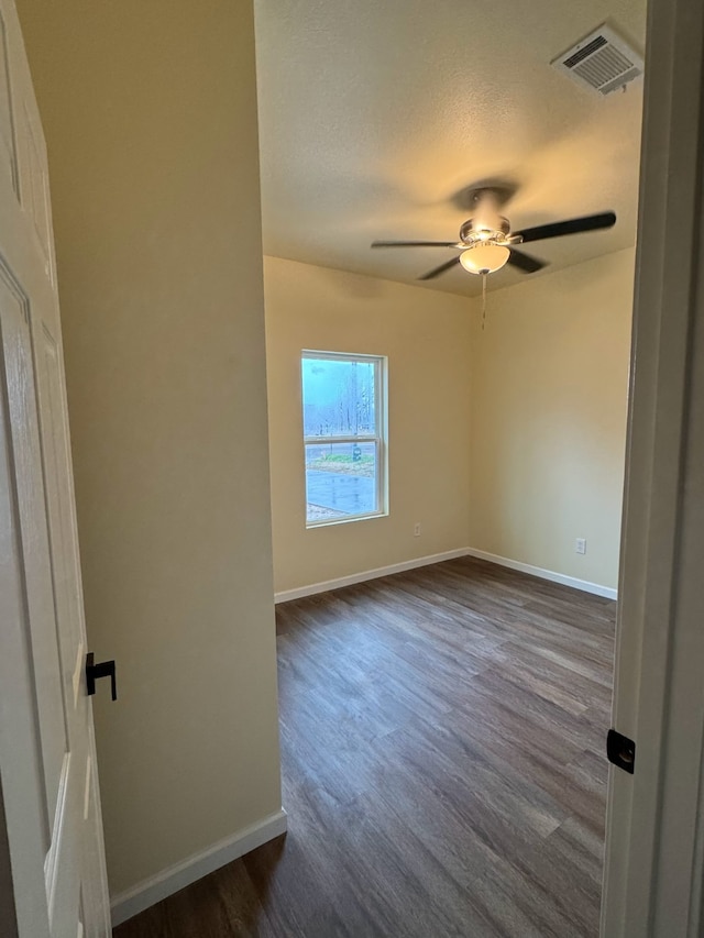 empty room with a textured ceiling, dark hardwood / wood-style floors, and ceiling fan