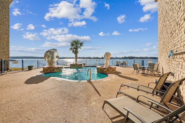 community pool with a water view, a patio, and fence