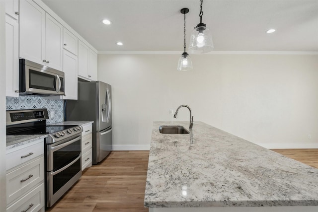 kitchen featuring white cabinetry, sink, hanging light fixtures, and appliances with stainless steel finishes