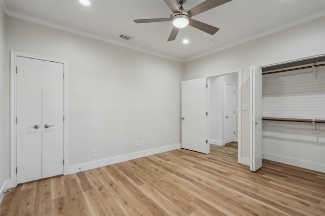 unfurnished bedroom with visible vents, light wood-style flooring, two closets, and ornamental molding