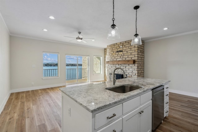 kitchen with sink, white cabinetry, a kitchen island with sink, ornamental molding, and stainless steel dishwasher