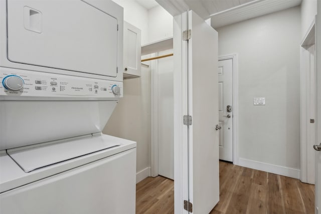 laundry room featuring light wood-type flooring and stacked washer / dryer