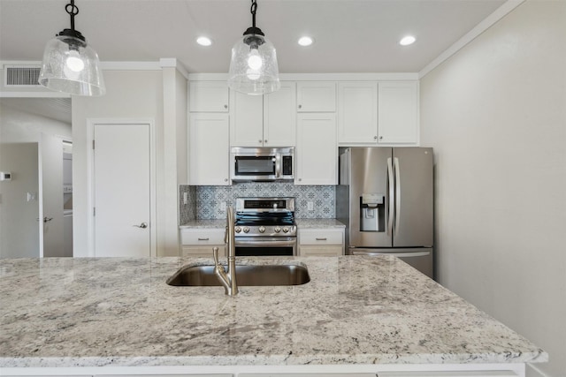 kitchen with appliances with stainless steel finishes, sink, white cabinets, and decorative light fixtures