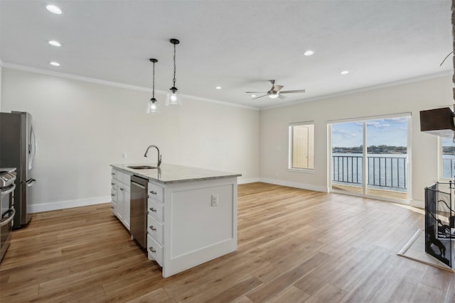 kitchen featuring light stone countertops, light wood-style flooring, appliances with stainless steel finishes, white cabinetry, and a sink