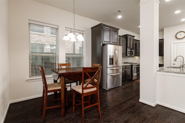 dining room featuring sink, dark hardwood / wood-style floors, and ornate columns