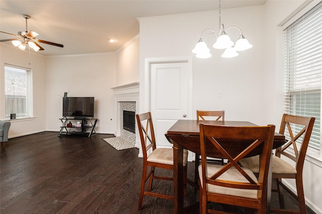 dining room featuring crown molding, dark hardwood / wood-style floors, ceiling fan with notable chandelier, and a tile fireplace