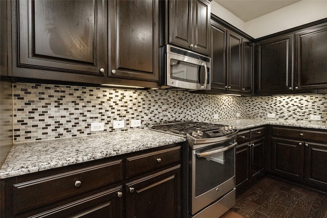 kitchen with tasteful backsplash, light stone countertops, dark brown cabinetry, and appliances with stainless steel finishes