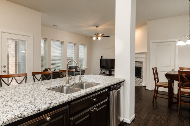 kitchen featuring sink, light stone counters, ornamental molding, dishwasher, and a tiled fireplace